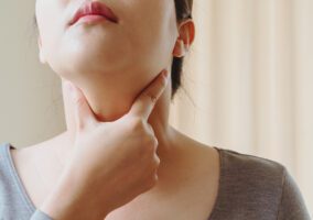 Woman touching her throat area to test thyroid condition