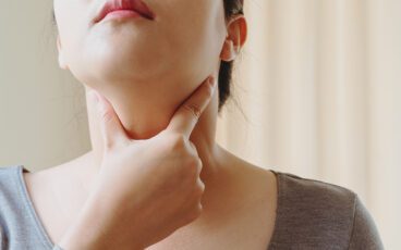 Woman touching her throat area to test thyroid condition