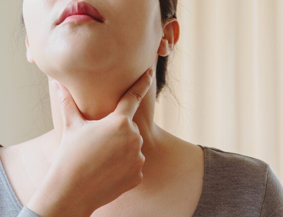 Woman touching her throat area to test thyroid condition
